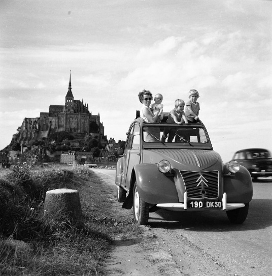 Famille en Citroën 2CV décapotée sur la route du Mont-Saint-Michel, photographie des années 1950-1960.