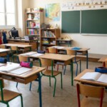 Salle de classe d’école élémentaire vide, pupitres, trousses et cahiers ouverts